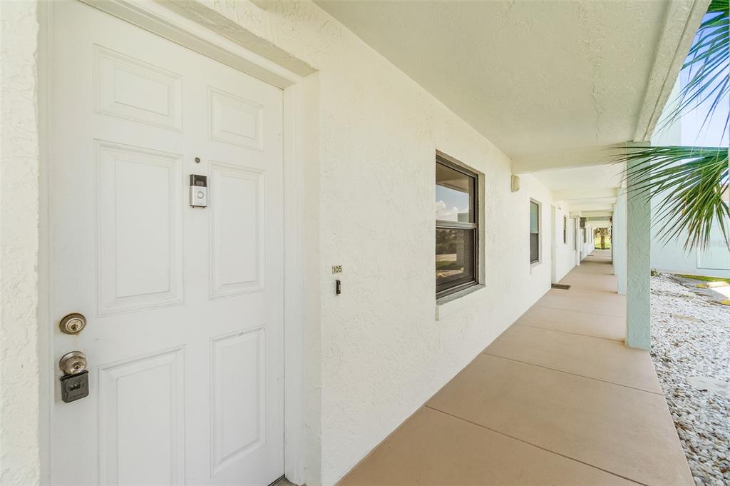 A white front door with a keypad lock is located on a covered outdoor walkway — 3390 OCEAN SHORE BOULEVARD UNIT 1050, ORMOND BEACH, FL