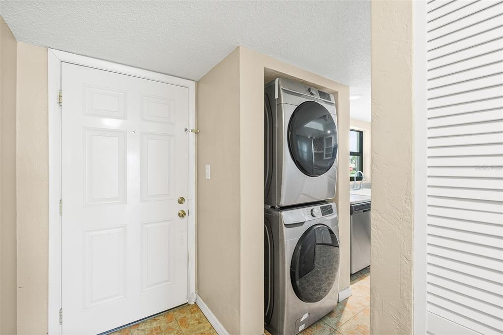 A white door stands next to a stacked washer and dryer in a small room — 3390 OCEAN SHORE BOULEVARD UNIT 1050, ORMOND BEACH, FL