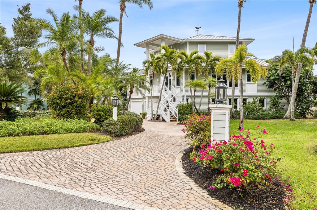 A multi-story, light green house with a paver driveway and palm trees in the yard — 16 GROUPER HOLE DRIVE, BOCA GRANDE, FL