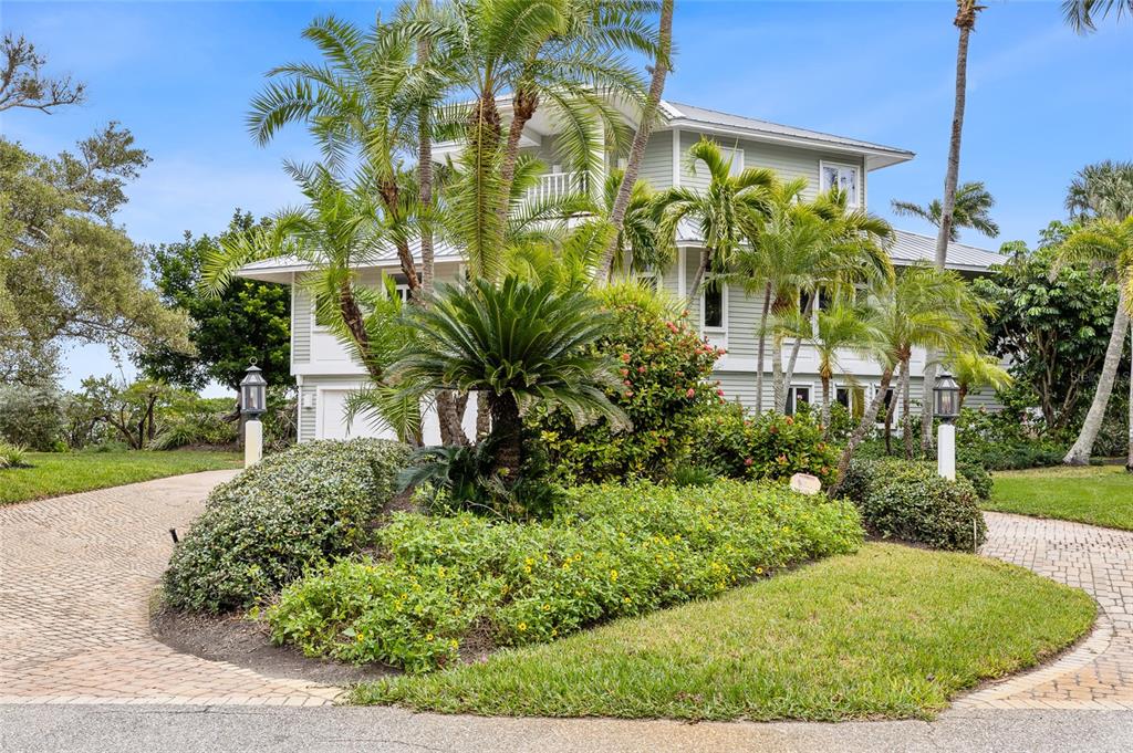 A light green multi-story house with a paved driveway and lush tropical landscaping — 16 GROUPER HOLE DRIVE, BOCA GRANDE, FL