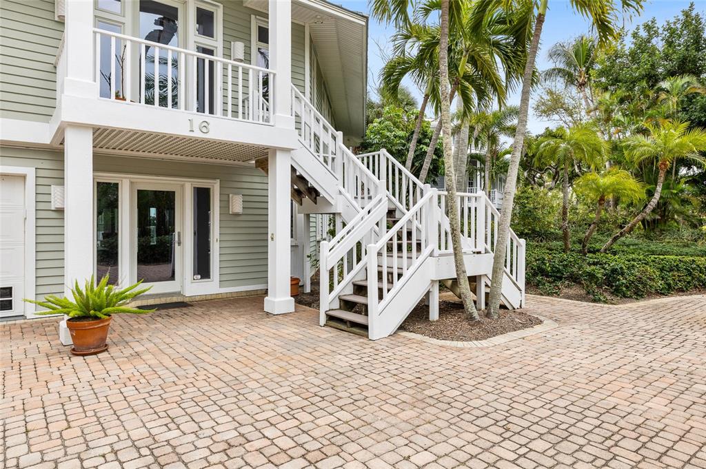 An exterior view of a house with light green siding, a brick driveway, and white stairs — 16 GROUPER HOLE DRIVE, BOCA GRANDE, FL