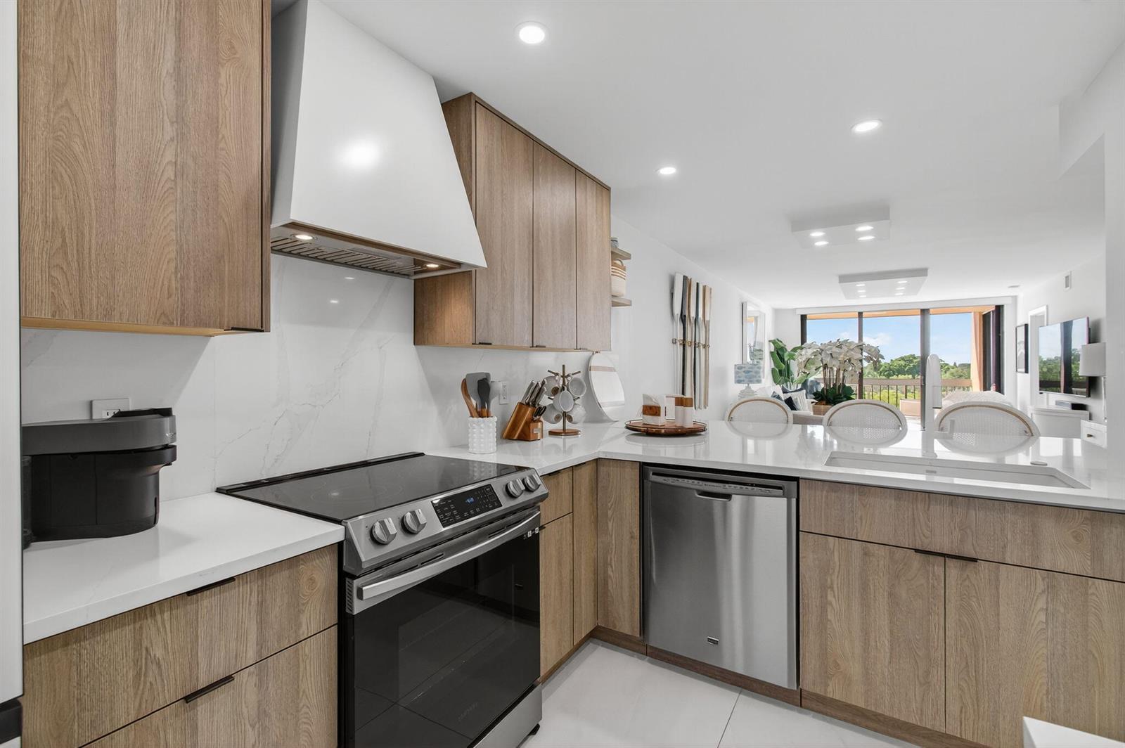 A modern kitchen features wood-grain cabinets, white marble-style backsplash, and stainless steel appliances — 600 Egret Circle # 7501, Delray Beach FL 33444, DELRAY BEACH, FL
