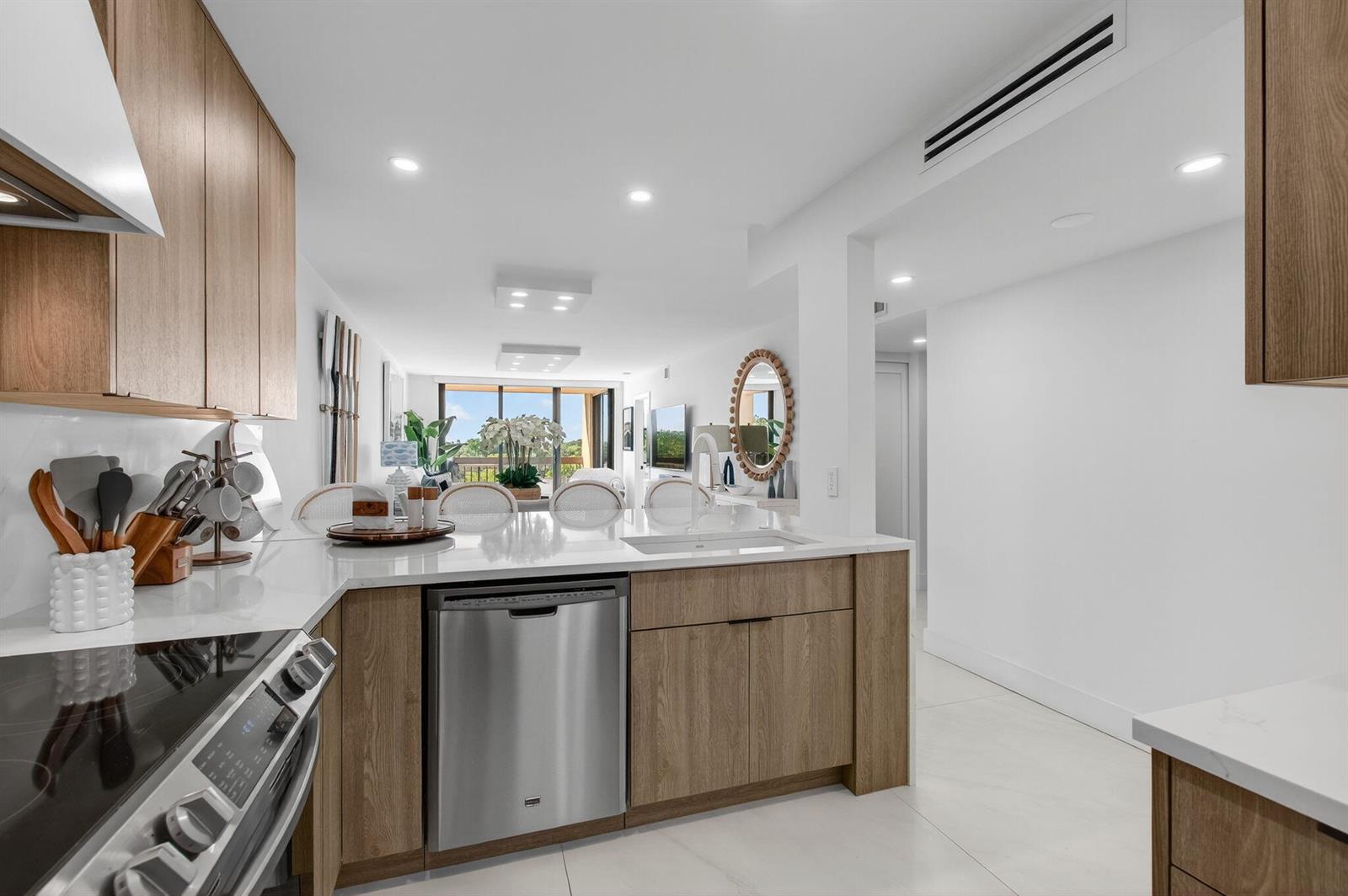 A modern kitchen with light wood cabinets, white countertops, and stainless steel appliances — 600 Egret Circle # 7501, Delray Beach FL 33444, DELRAY BEACH, FL