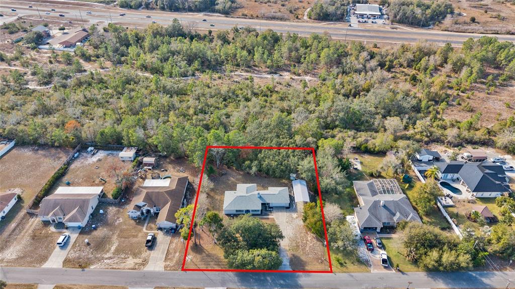 An aerial view shows a single-story house with a driveway and yard outlined in red — 7095 BLACKBIRD AVENUE, WEEKI WACHEE, FL