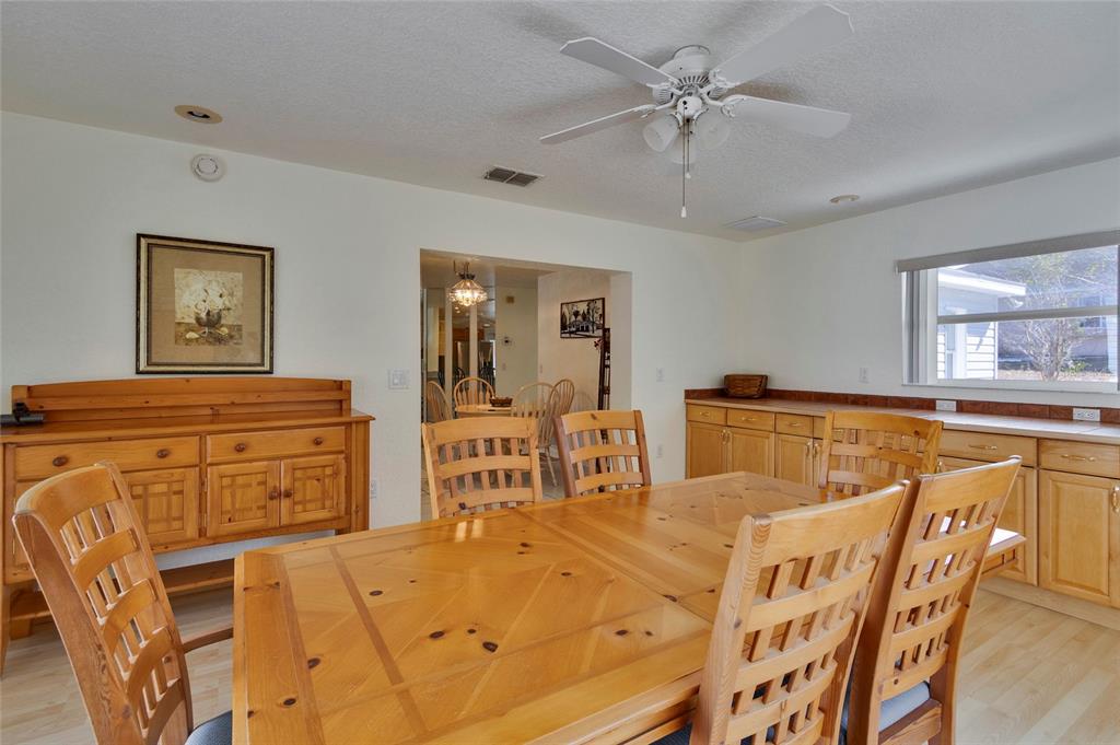 A dining room features a wooden table and chairs, a matching sideboard, and light cabinetry — 7095 BLACKBIRD AVENUE, WEEKI WACHEE, FL