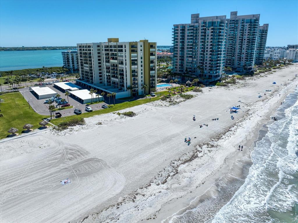 An aerial view of beachfront high-rise condominiums with a parking lot and sandy beach — 1480 GULF BOULEVARD UNIT 401, CLEARWATER BEACH, FL