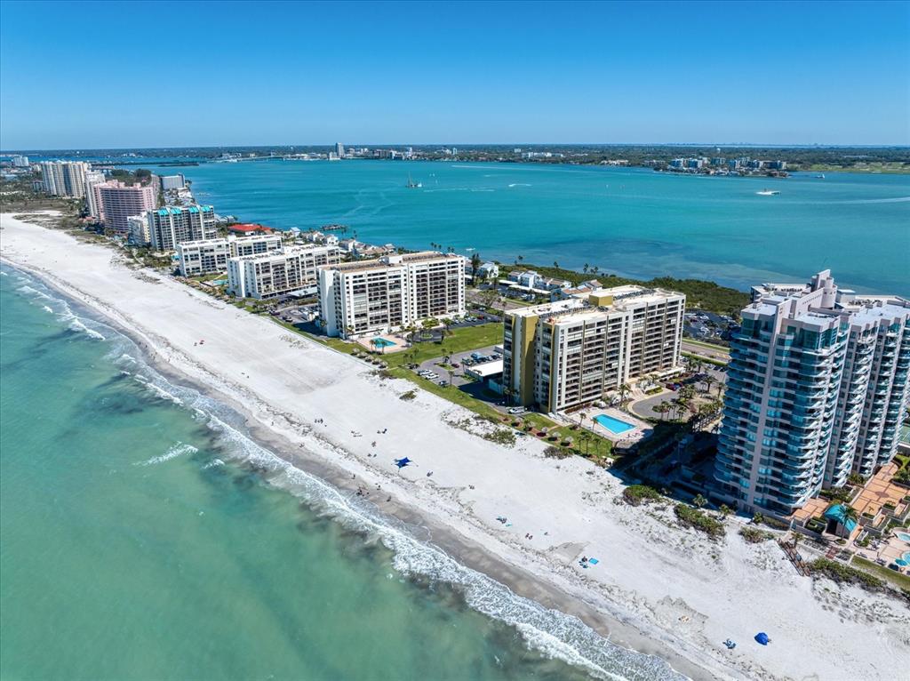 An aerial view of a sandy beach lined with high-rise residential buildings along the coast — 1480 GULF BOULEVARD UNIT 401, CLEARWATER BEACH, FL