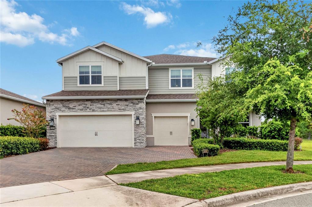A two-story suburban house with a three-car garage, stone facade, and a paved driveway — 13485 PANAMA BEACH COURT, ORLANDO, FL