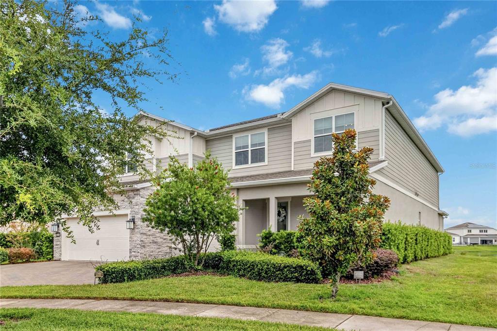 A two-story suburban house with gray siding, stone accents, a garage, and a manicured lawn — 13485 PANAMA BEACH COURT, ORLANDO, FL