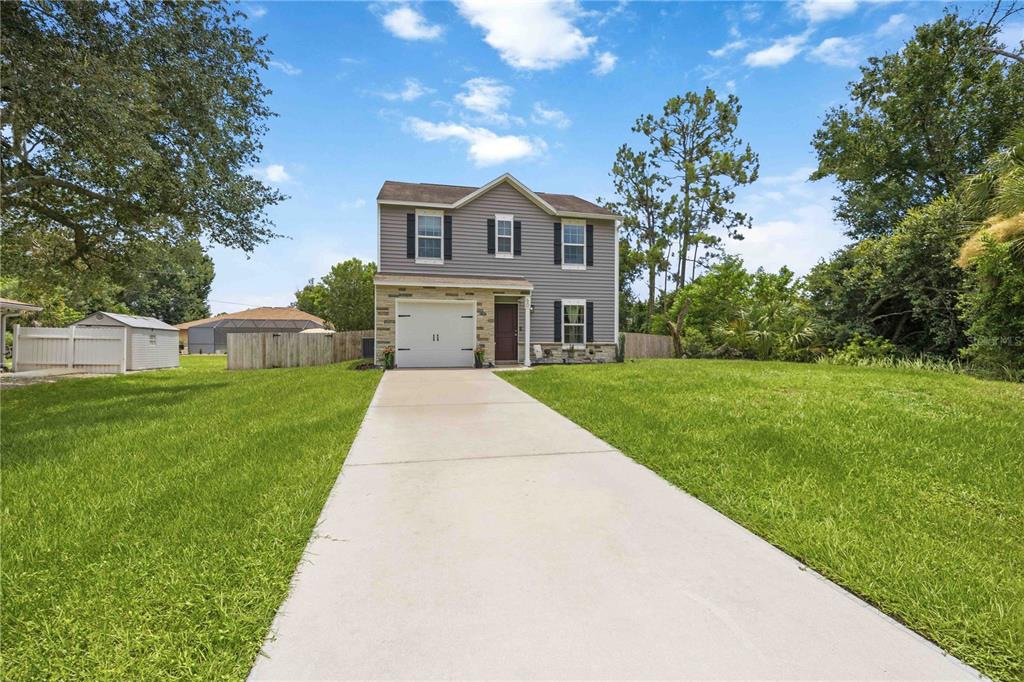 An aerial view shows a two-story gray house with a driveway and surrounding trees — 60 INDEPENDENCE STREET, PORT CHARLOTTE, FL