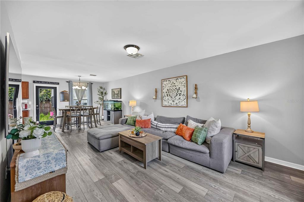 A living room features a grey sectional sofa, a large wall-mounted television, and wood flooring — 60 INDEPENDENCE STREET, PORT CHARLOTTE, FL