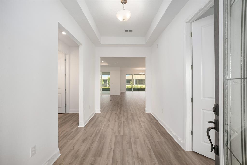 A bright entryway with wood-look flooring leads to an open living area with large windows — 10187 SW 84TH LANE, OCALA, FL