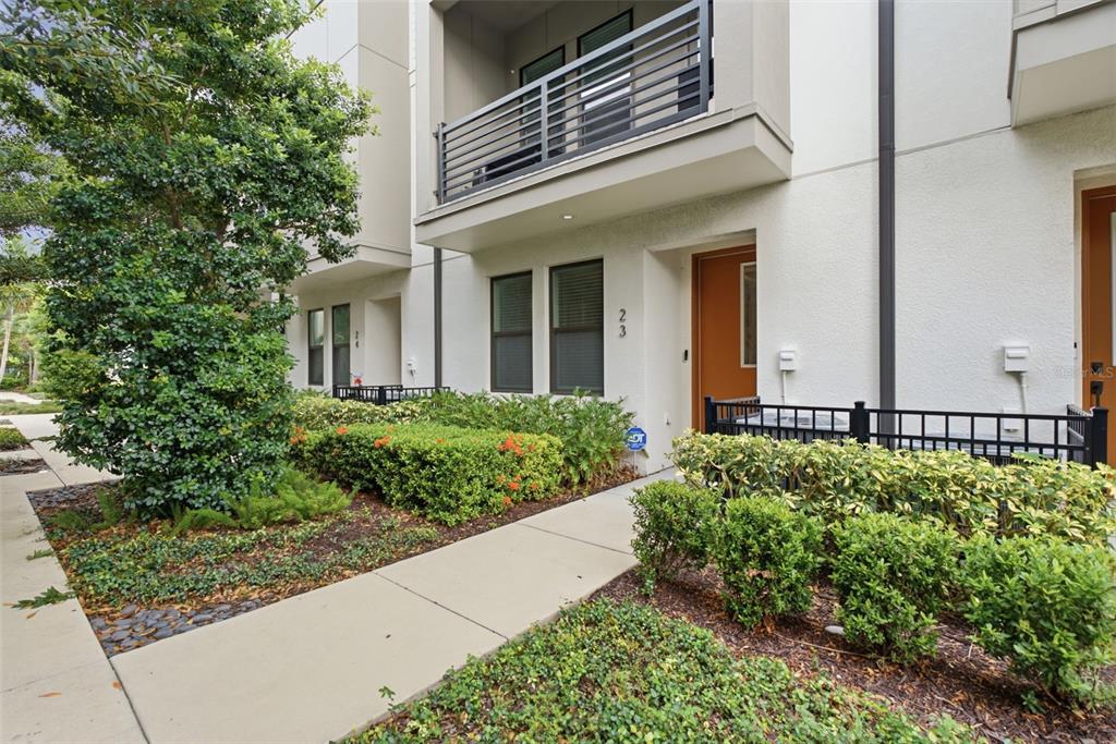 A modern townhome exterior features a brown front door, a balcony, and landscaped shrubbery — 2511 N GRADY AVENUE UNIT 23, TAMPA, FL