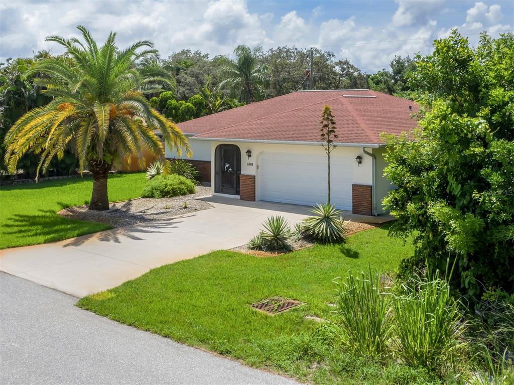 A single-story house with a red roof, white garage door, and a large palm tree — 1211 SOUTHLAND ROAD, VENICE, FL
