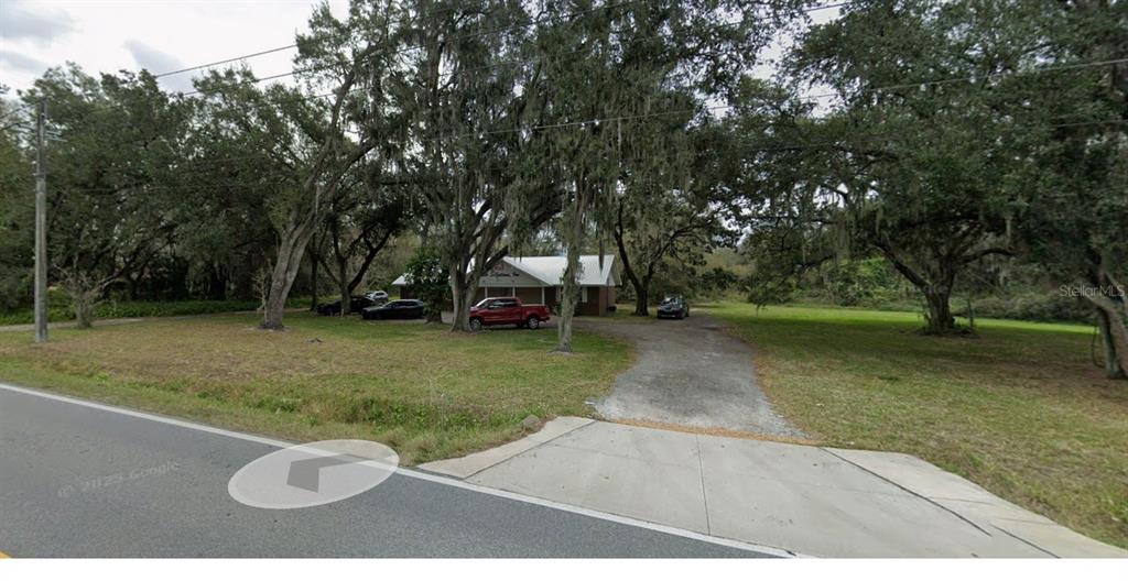 A single-story house sits on a large, tree-shaded lot with a paved driveway — 4040 WARING ROAD, LAKELAND, FL