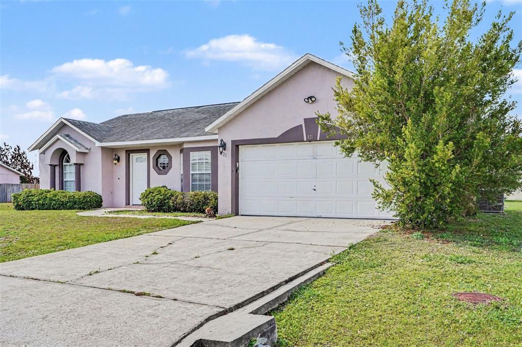 A single-story house with a white garage door, light-colored stucco walls, and a concrete driveway — 821 JARNAC DRIVE, KISSIMMEE, FL