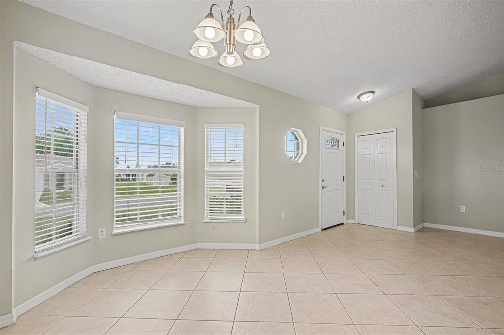 A bright dining area features tile flooring, a bay window, and a chandelier — 821 JARNAC DRIVE, KISSIMMEE, FL