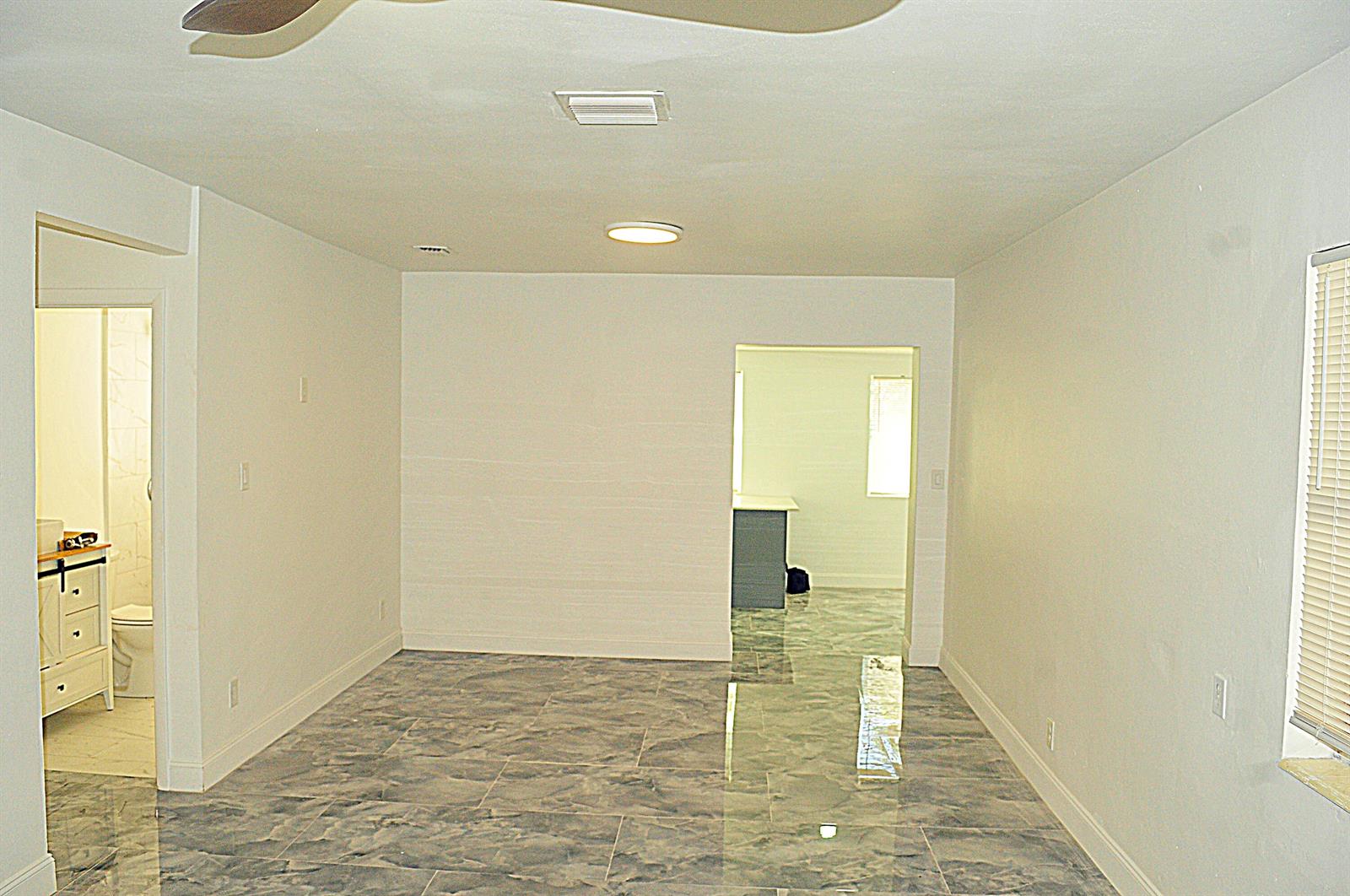 A room with gray marble-look tile flooring, white walls, a ceiling fan, and two doorways — 936 45th Street, West Palm Beach FL 33407, WEST PALM BEACH, FL