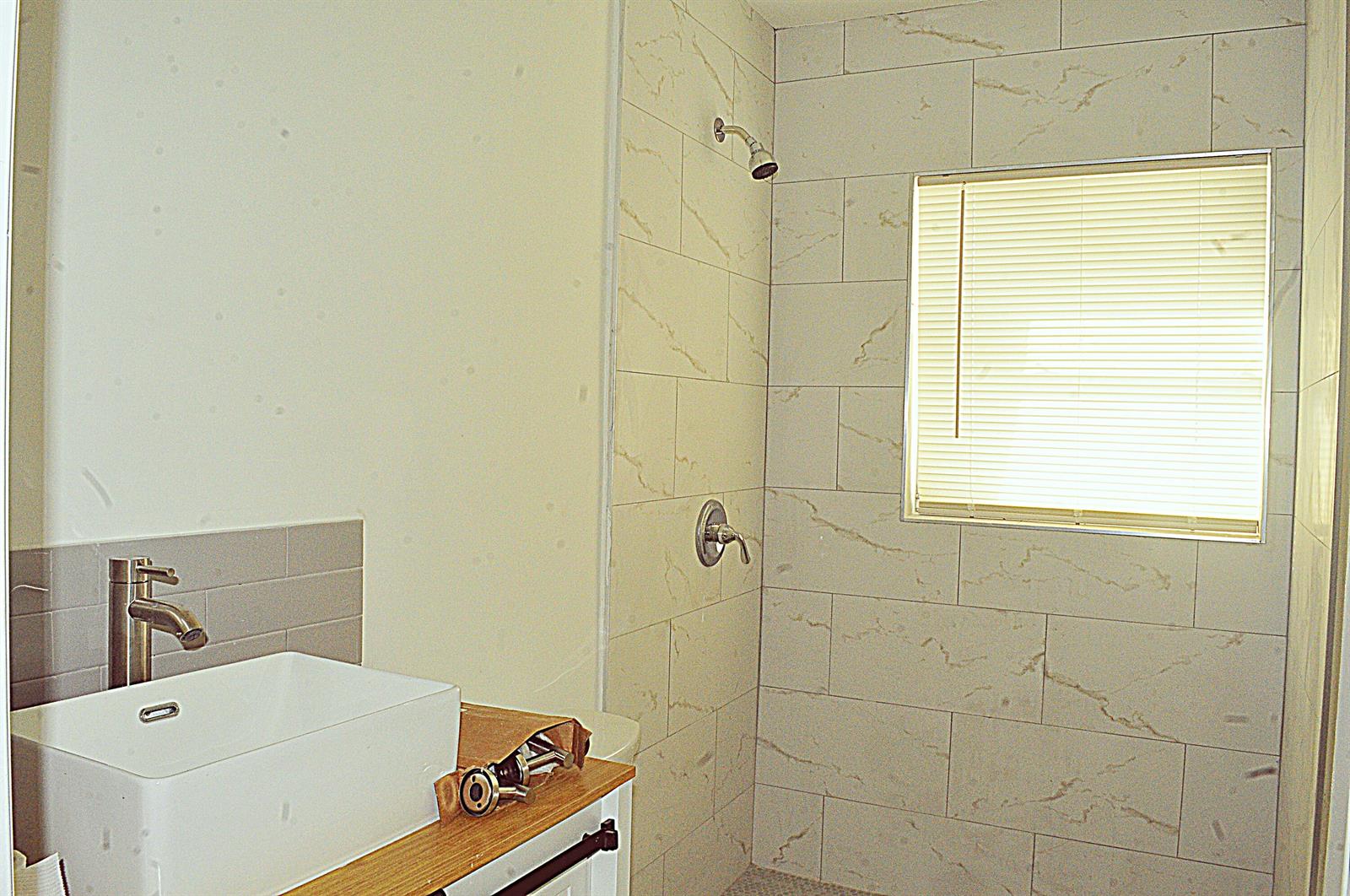 A bathroom features a vessel sink vanity and a tiled walk-in shower with a window — 936 45th Street, West Palm Beach FL 33407, WEST PALM BEACH, FL