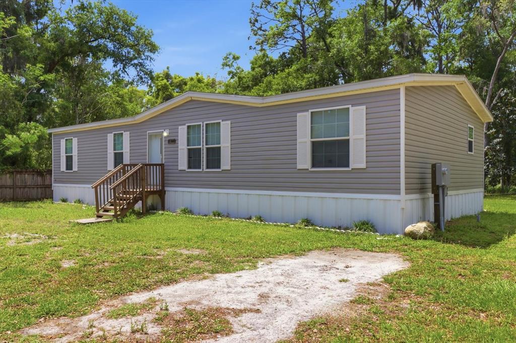 A single-story manufactured home with gray vinyl siding and a wooden front porch — 1140 NW 110TH COURT, OCALA, FL