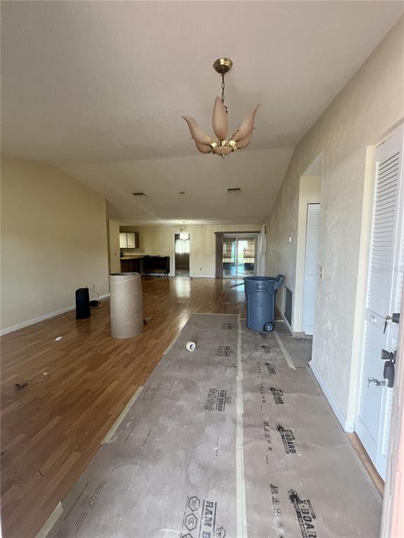An open-concept living area features wood flooring, a chandelier, and protective floor covering — 2 SENECA PATH, PALM COAST, FL