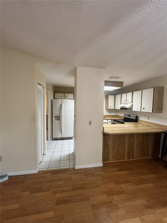 A kitchen features wood-look laminate flooring, a breakfast bar, white cabinets, and a white refrigerator — 2 SENECA PATH, PALM COAST, FL
