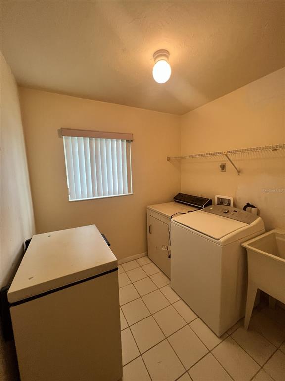 A laundry room features a white washer, a chest freezer, a utility sink, and tile flooring — 2 SENECA PATH, PALM COAST, FL