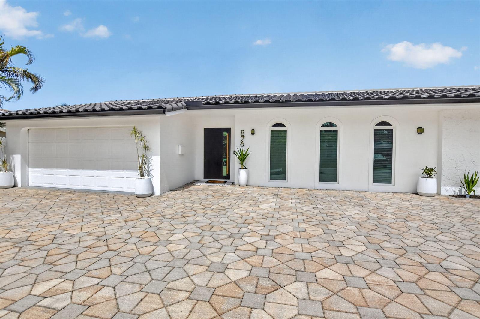 A white single-story house features a tiled roof, arched windows, and a paved driveway — 876 NW 6th Avenue, Boca Raton FL 33432, BOCA RATON, FL