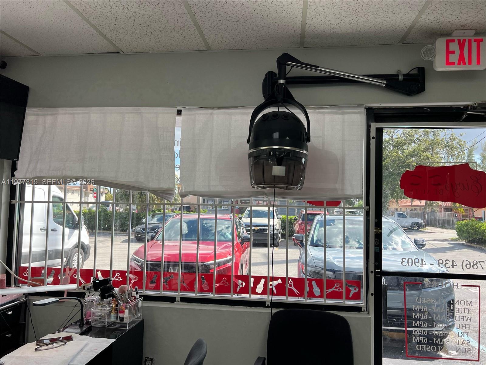 A hair salon features a wall-mounted dryer, white window shades, and a view of a parking lot — 3300 E 4 AVE, Hialeah FL 33013, HIALEAH, FL
