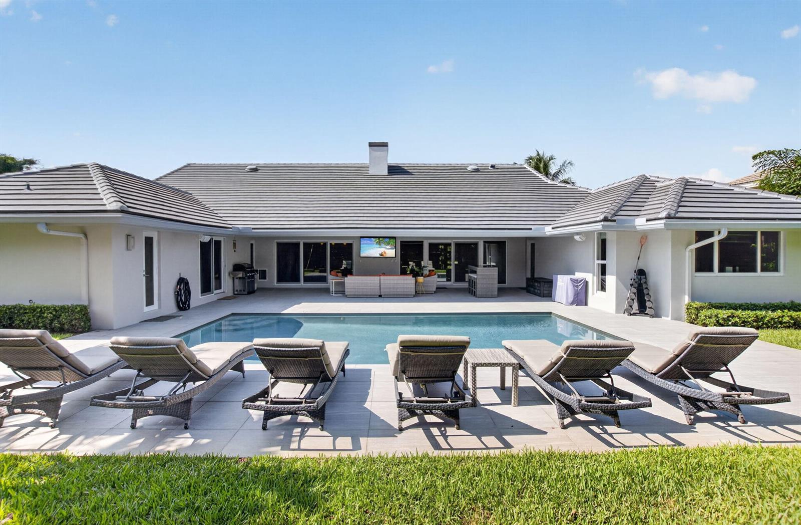 A backyard features a swimming pool, lounge chairs on a patio, and a covered seating area — 3245 St James Drive, Boca Raton FL 33434, BOCA RATON, FL