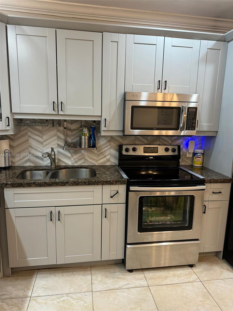 A kitchen features light gray cabinets, stainless steel appliances, and a herringbone-patterned tile backsplash — 3725 S Ocean Dr # L12, Hollywood FL 33019, HOLLYWOOD, FL
