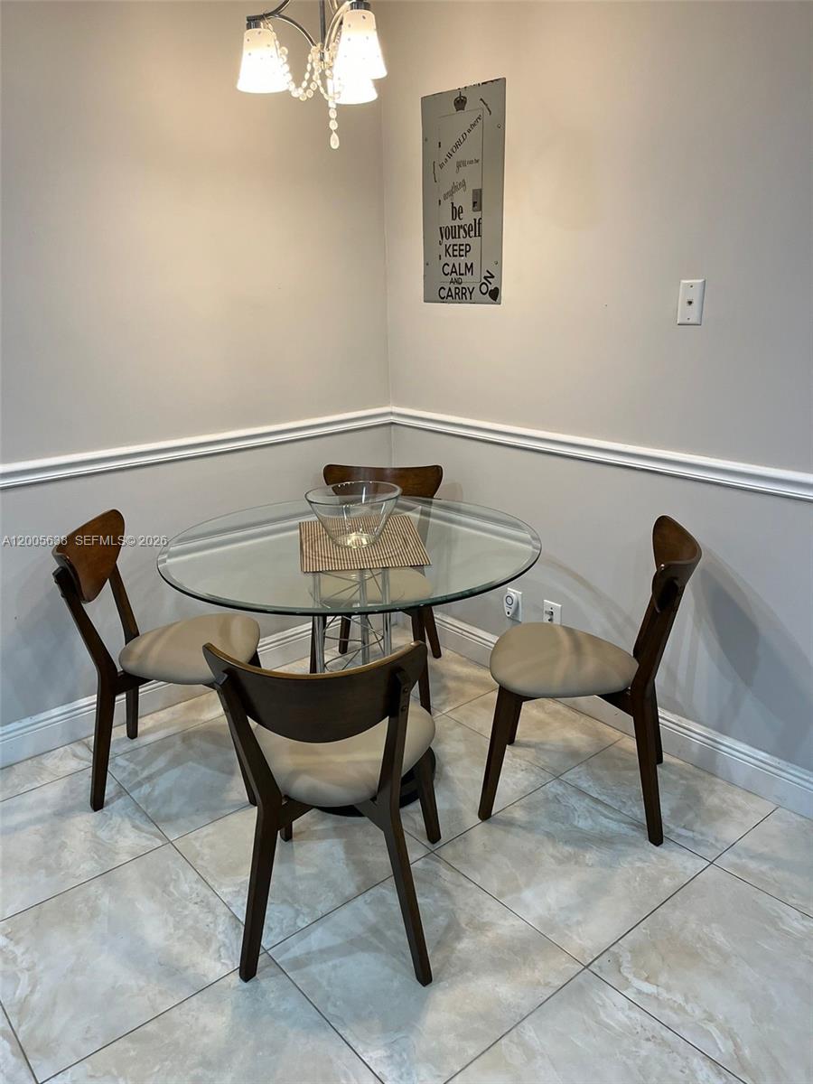 A dining area features a glass-topped table with four chairs and a wall-mounted sign — 3725 S Ocean Dr # L12, Hollywood FL 33019, HOLLYWOOD, FL