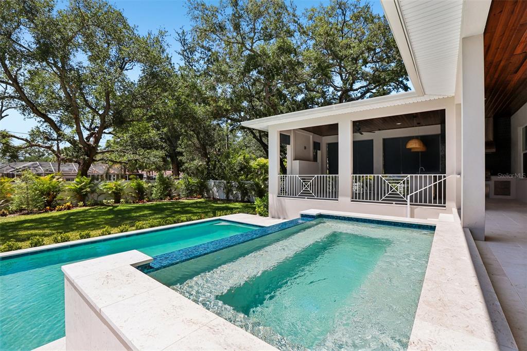 A swimming pool with a raised spa sits beside a covered patio and grassy yard — 3013 S WEST SHORE BOULEVARD, TAMPA, FL