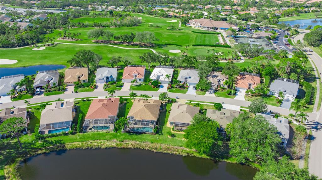 An aerial view shows a suburban neighborhood with houses bordering a golf course and lake — 8928 WHITEMARSH AVENUE, SARASOTA, FL