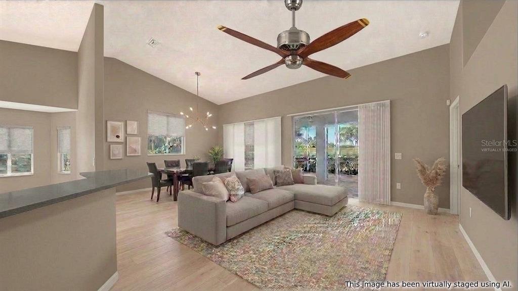 This virtually staged living room features light wood floors, a vaulted ceiling, and sliding doors — 8928 WHITEMARSH AVENUE, SARASOTA, FL