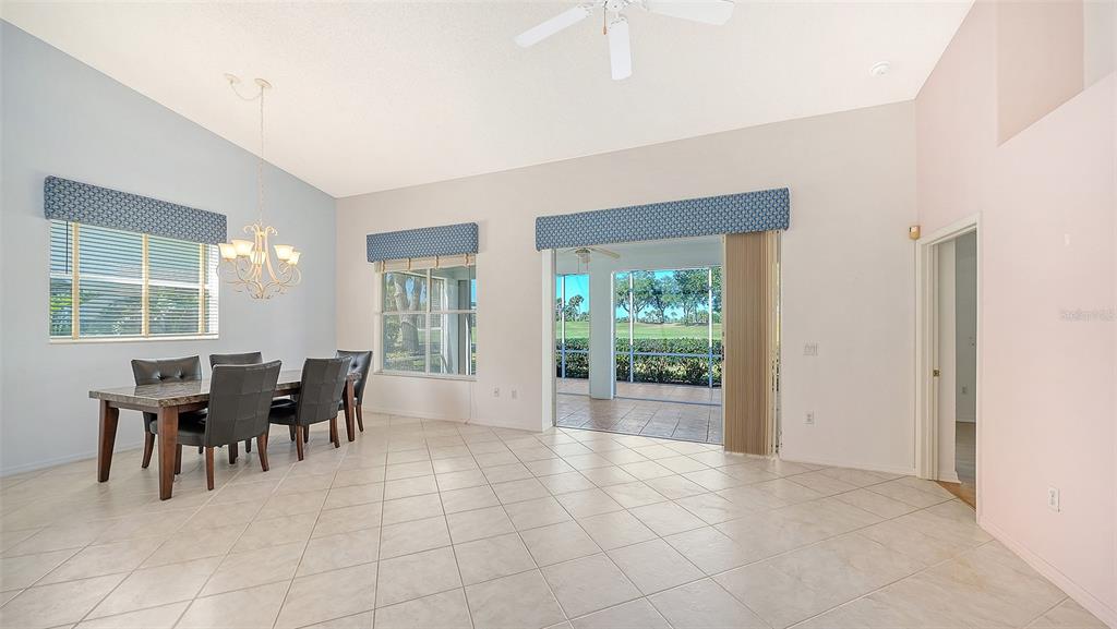 A dining area with tile floors, a chandelier, and sliding glass doors leading to a patio — 8928 WHITEMARSH AVENUE, SARASOTA, FL