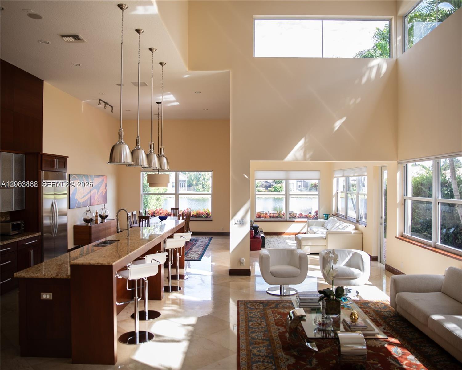 A spacious open-concept kitchen and living area features high ceilings, tile floors, and large windows — 2485 NW 66th Dr # 0, Boca Raton FL 33496, BOCA RATON, FL