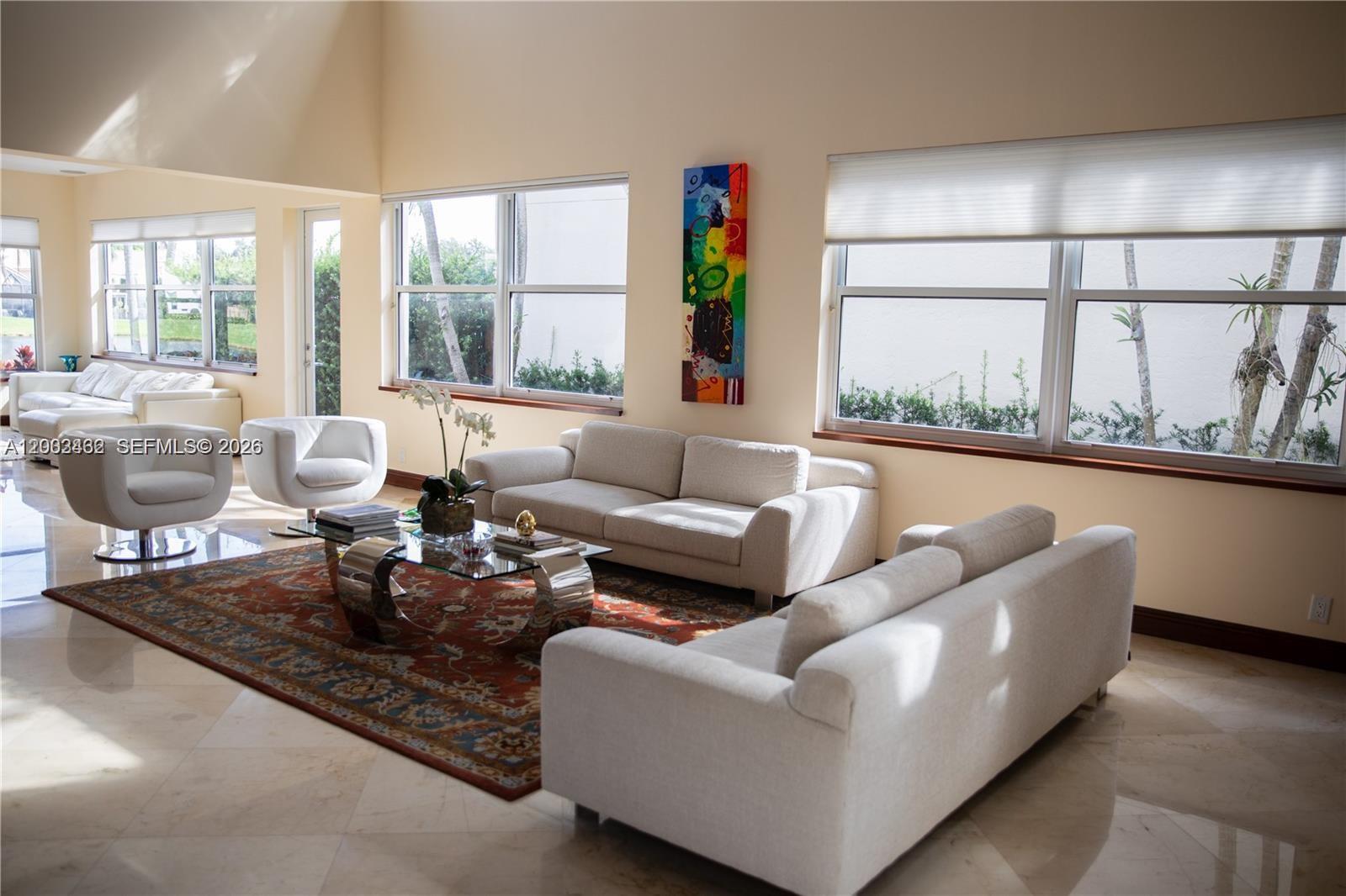 A bright living room features light-colored sofas, a glass coffee table, and large windows — 2485 NW 66th Dr # 0, Boca Raton FL 33496, BOCA RATON, FL