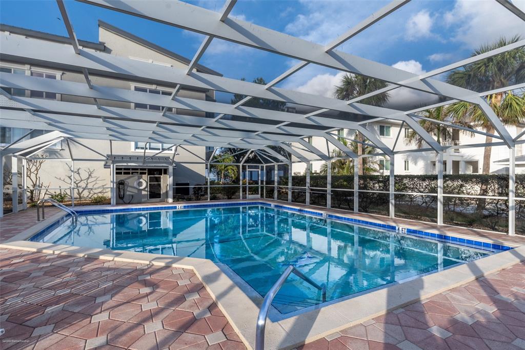 A rectangular swimming pool is enclosed by a white metal screen structure on a patio — 1477 PARK BEACH CIRCLE UNIT 33, PUNTA GORDA, FL