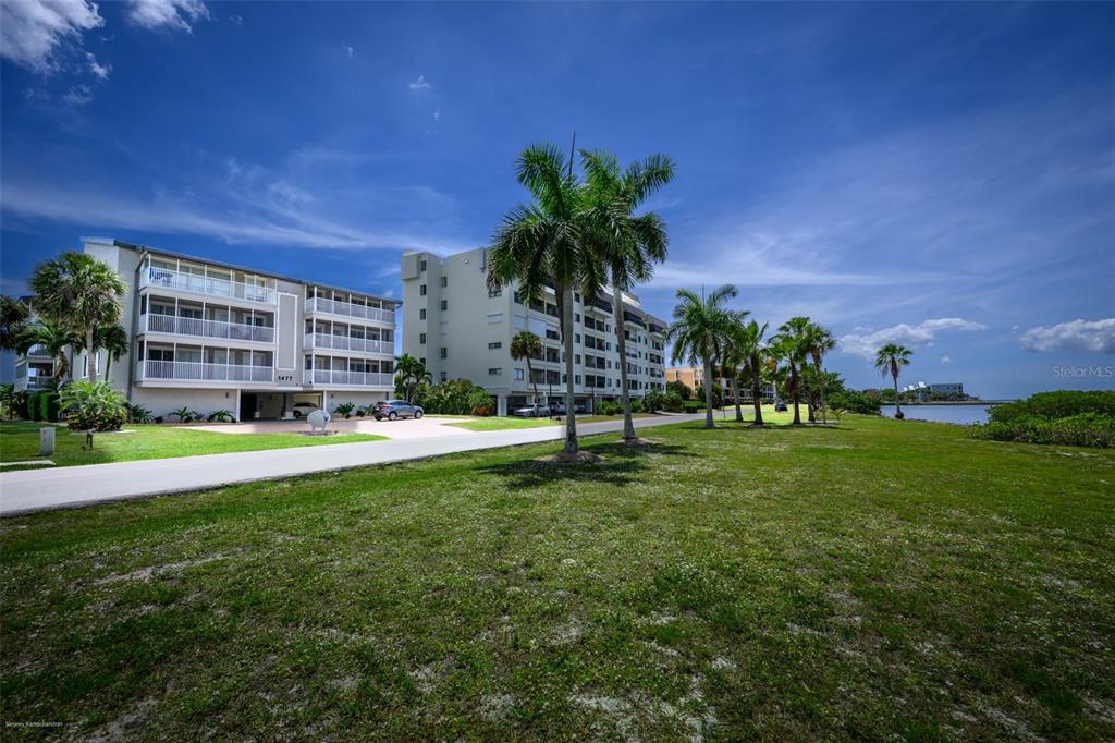 A multi-story apartment building sits next to a grassy lawn and palm trees near water — 1477 PARK BEACH CIRCLE UNIT 33, PUNTA GORDA, FL