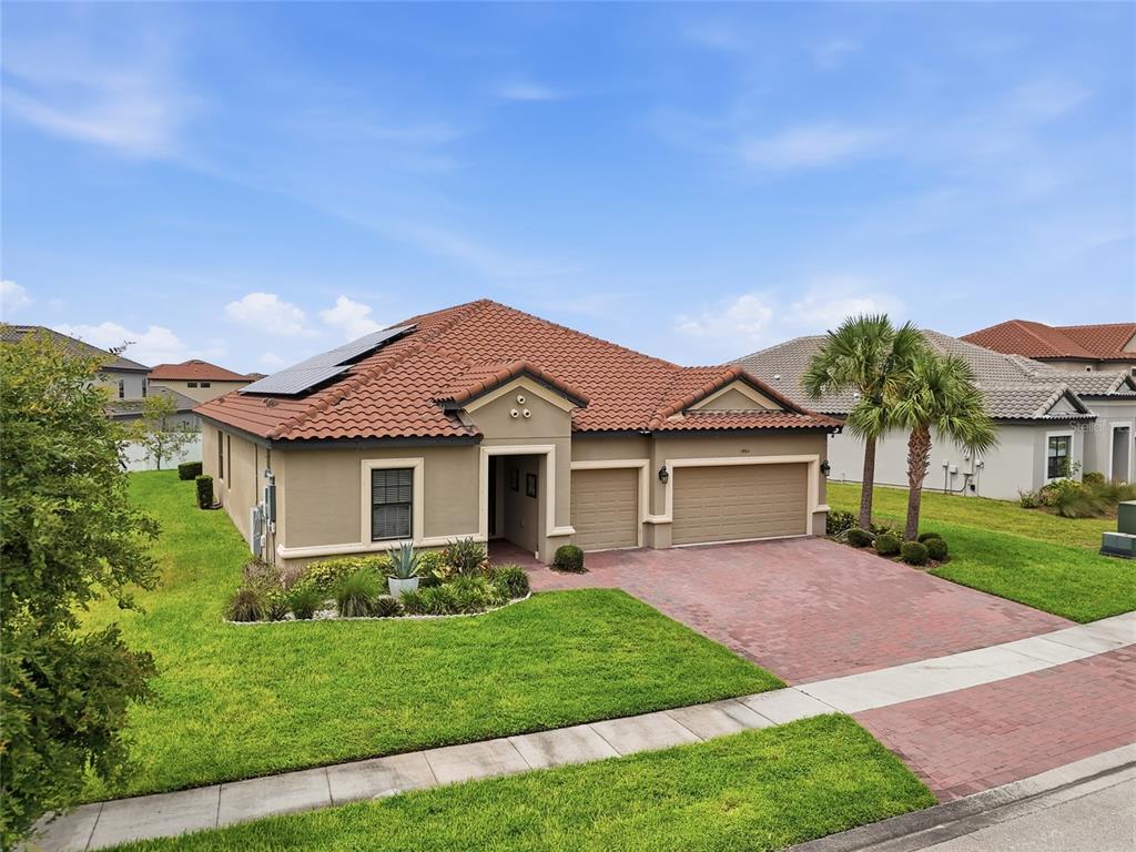 A single-story house with a tiled roof, solar panels, and a brick-paved driveway — 3865 BOWFIN TRAIL, KISSIMMEE, FL