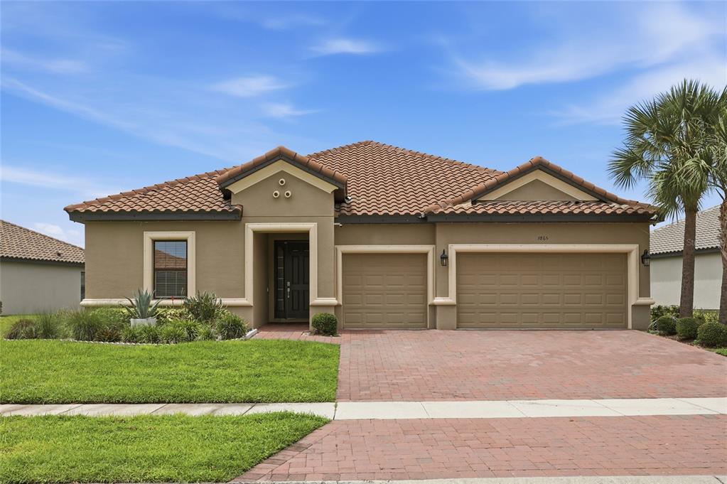 A single-story house with a tan stucco exterior, tile roof, and a brick paver driveway — 3865 BOWFIN TRAIL, KISSIMMEE, FL