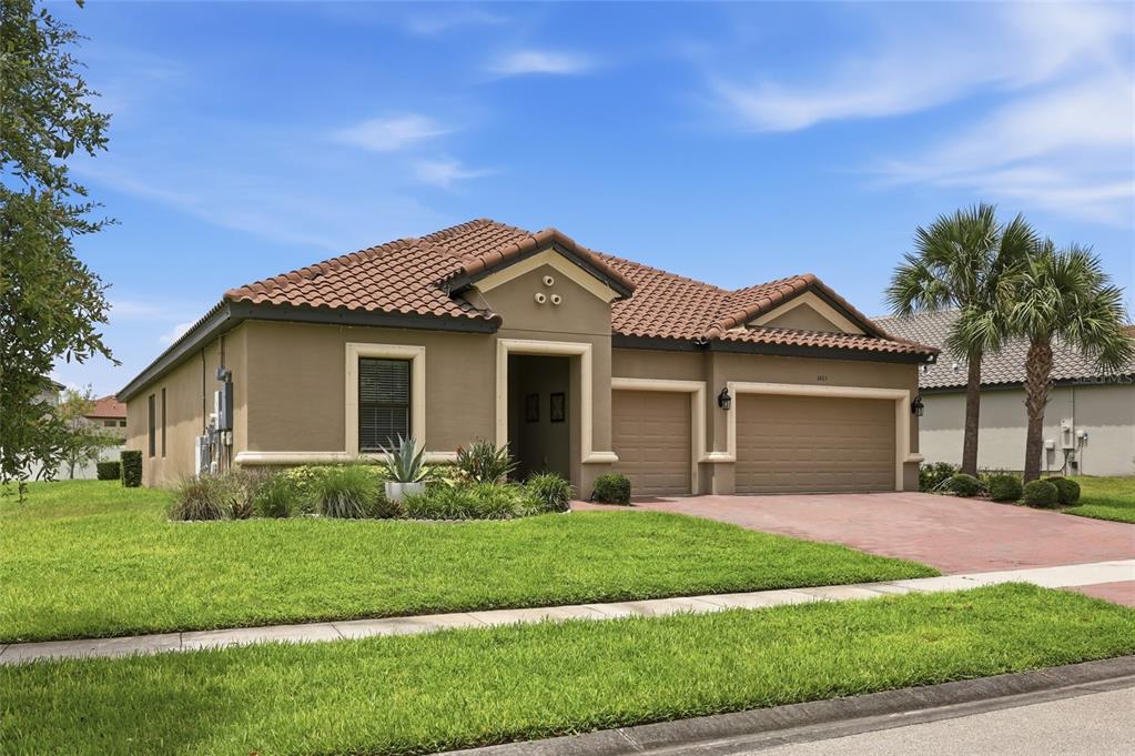 A tan, single-story house with a tile roof and a three-car garage sits on grass — 3865 BOWFIN TRAIL, KISSIMMEE, FL