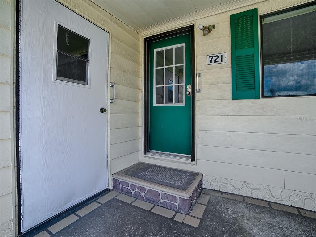 A white door and a green front door with a small step are visible — 721 SHARON DRIVE, LADY LAKE, FL
