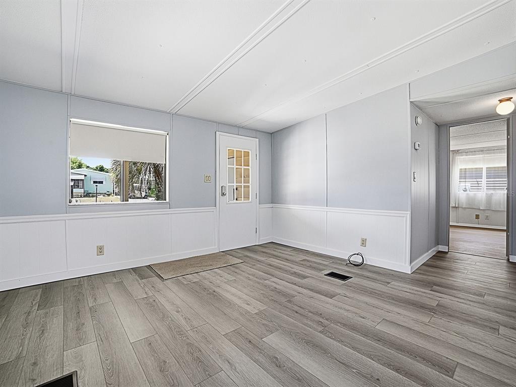 A living room with light gray walls, white wainscoting, and wood-look laminate flooring — 721 SHARON DRIVE, LADY LAKE, FL