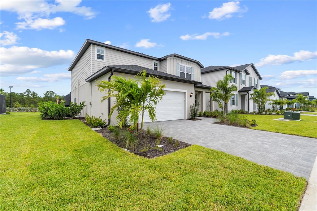A two-story suburban house with a paved driveway, a white garage door, and palm landscaping — 45012 PIPEVINE CIRCLE, PUNTA GORDA, FL