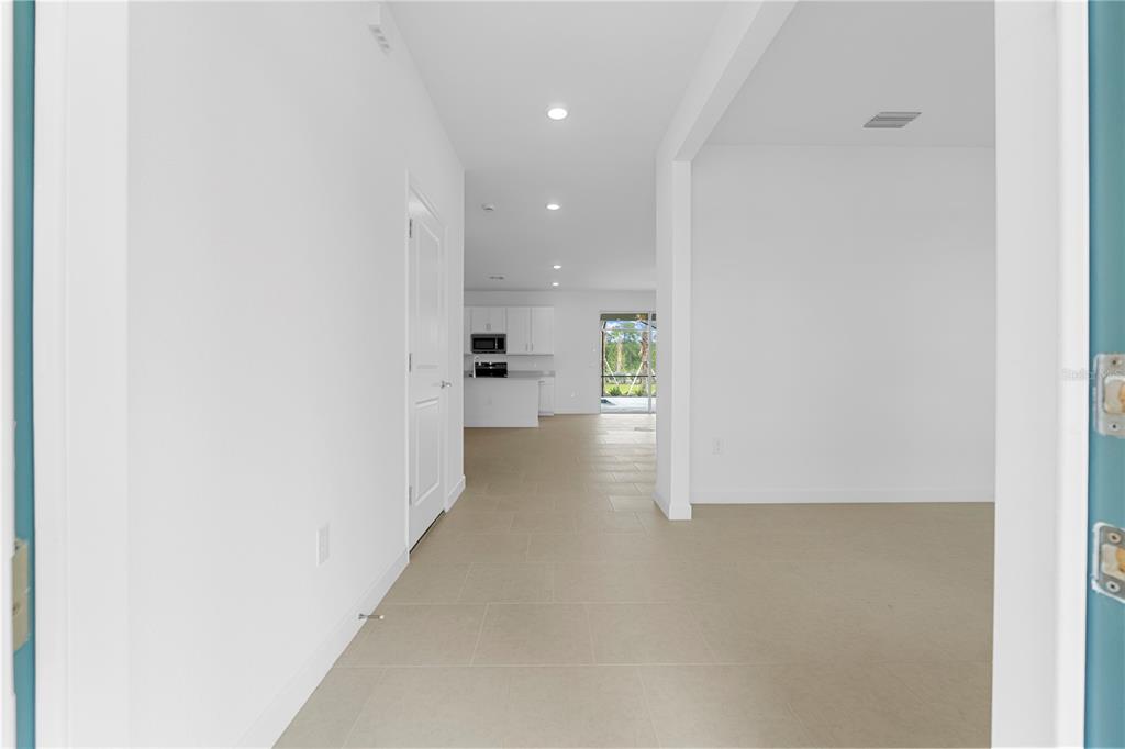 A view from a doorway looking down a hallway toward an open-concept kitchen and patio — 45012 PIPEVINE CIRCLE, PUNTA GORDA, FL