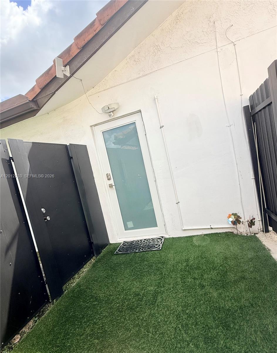 A white door with a frosted glass panel opens onto a small artificial turf patio — MIAMI, FL