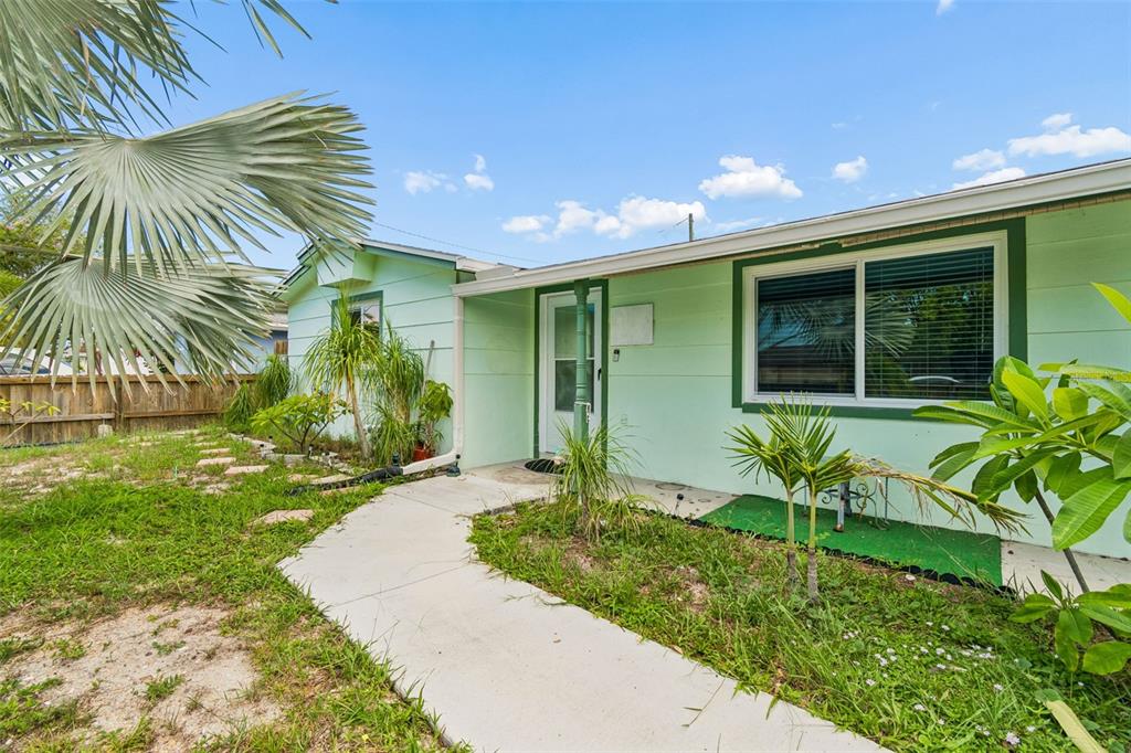 A light green house with a concrete walkway leading to the front entrance — 1056 TAMARAC DRIVE, HOLIDAY, FL