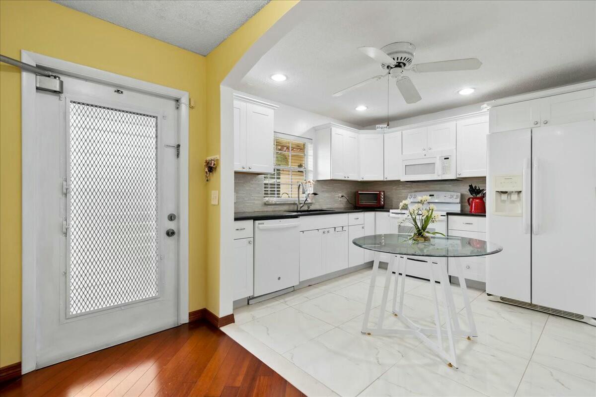 A kitchen with white cabinets, stainless steel appliances, a glass table, and white tile flooring — 603 Laconia Circle, Lake Worth FL 33467, LAKE WORTH, FL